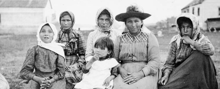 Women and children [of Brunswick House First Nation] at the feast during Treaty 9 payment ceremony at [the Hudson’s Bay Company Post called] New Brunswick House, Ontario.